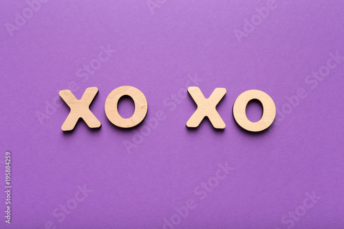 Wooden letters spelling xo-xo on violet background