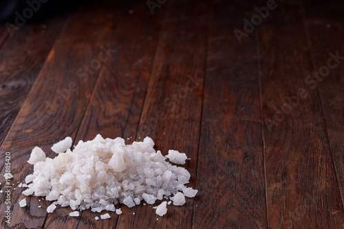 Pile of salt crystals on the dark wooden background, top view, flat lay, shallow depth of field