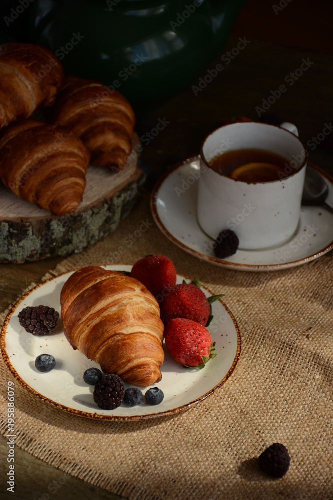 The freshly baked croissants for breakfast with berries and green tea 