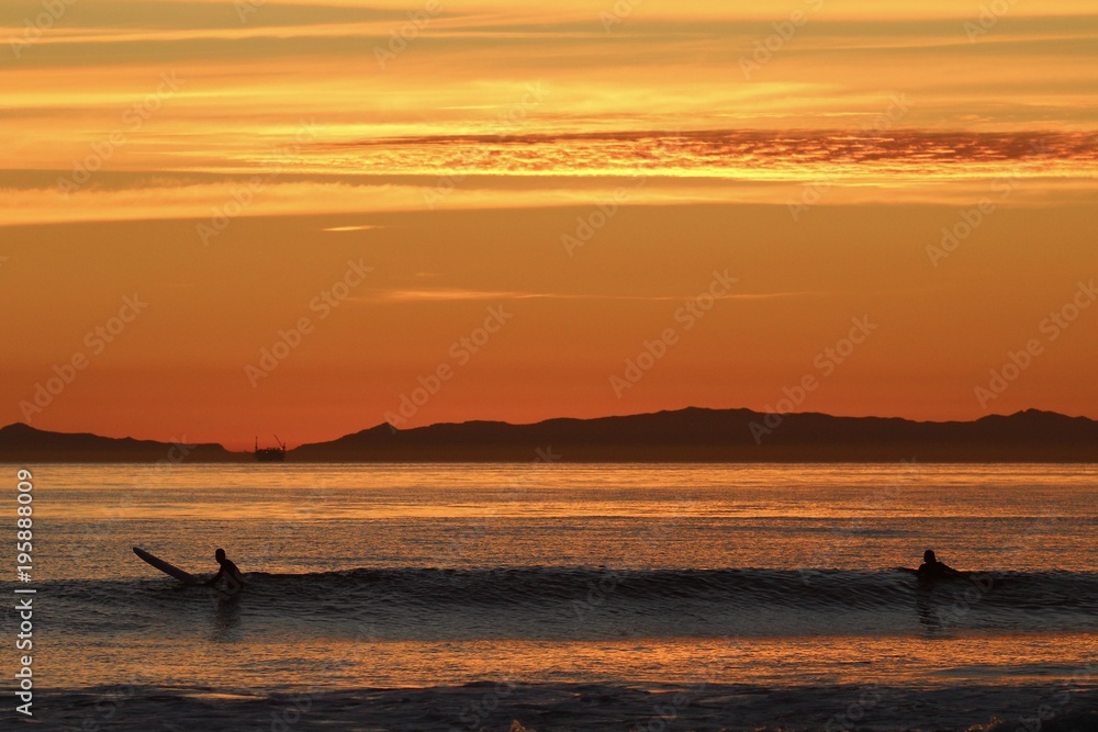 silhouettes of surfers during a california sunset