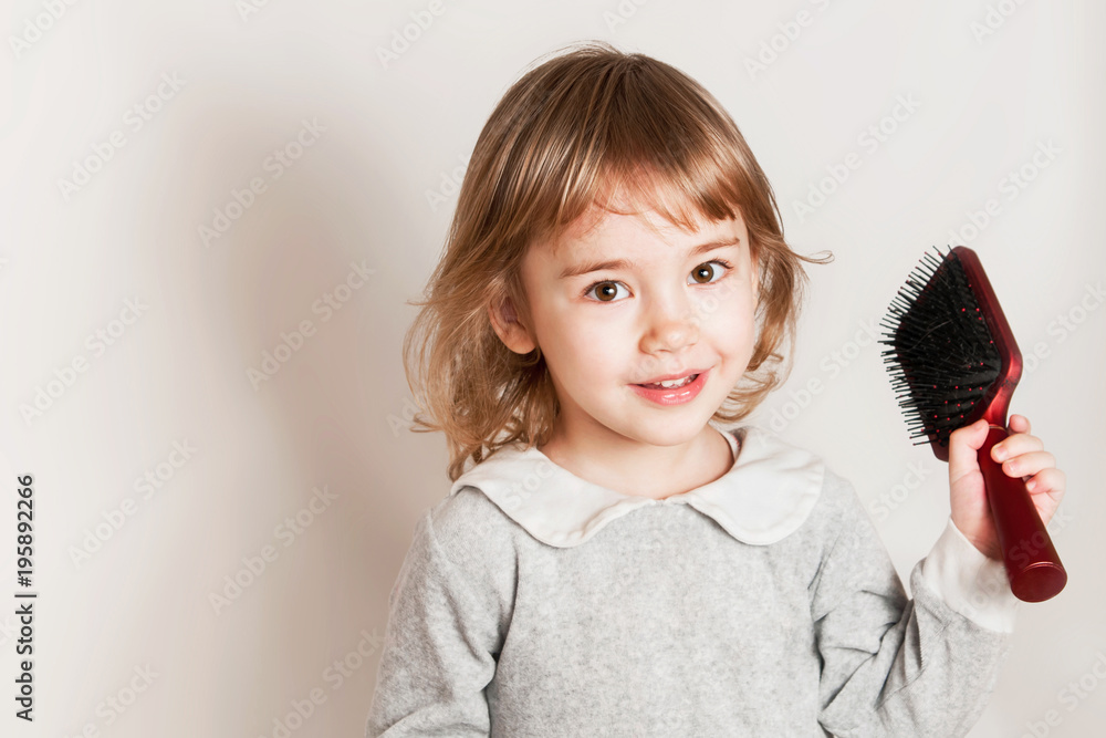 Little baby girl holds comb and combing her hair on light background. Stock  Photo | Adobe Stock