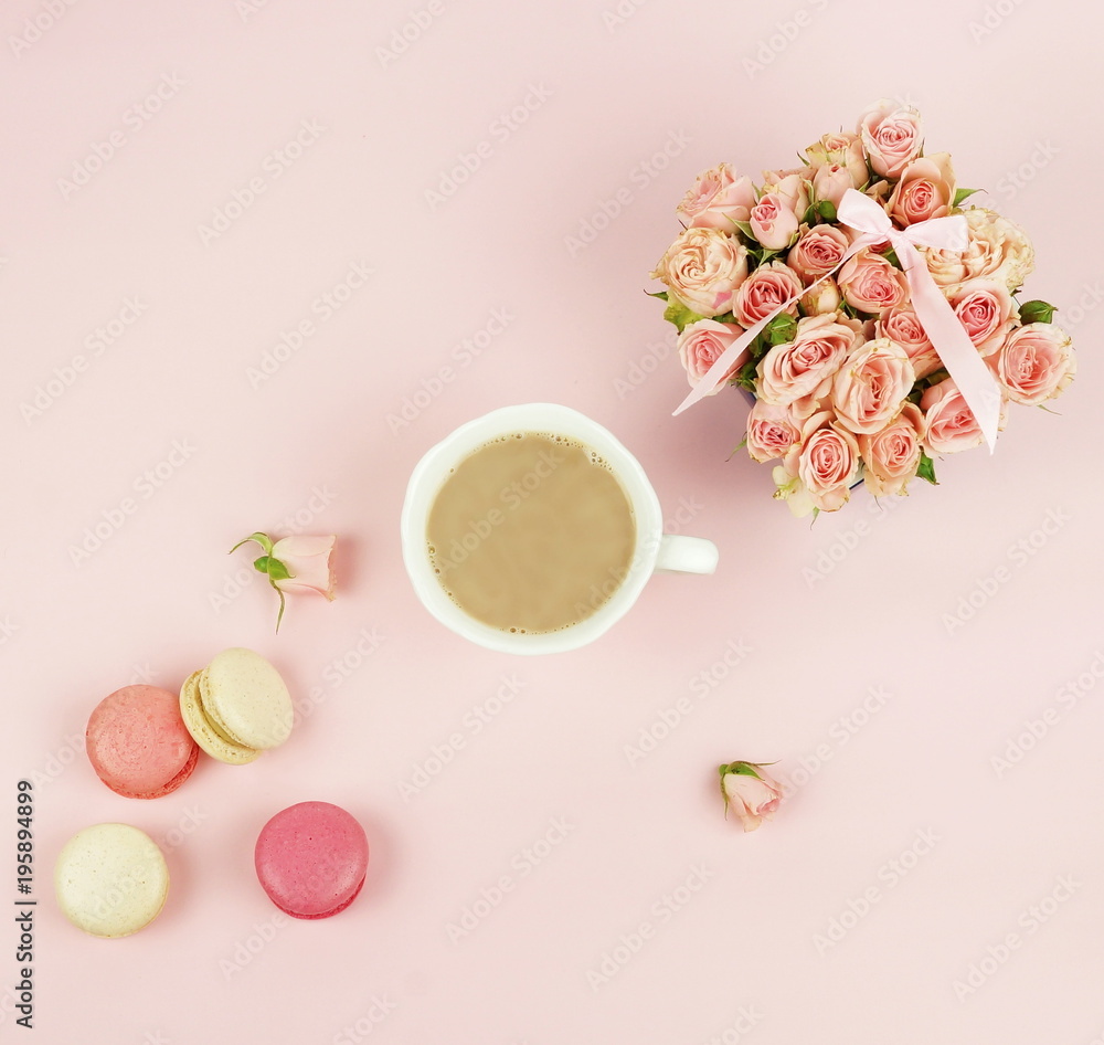 macaroons in pastel colors with bouquet pink roses  flowers and cup of cocoa on a pale pink background.Holiday background.copy space.top view