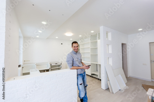 Surprised architect talking on the mobile phone with laptop in the hand indoors photo