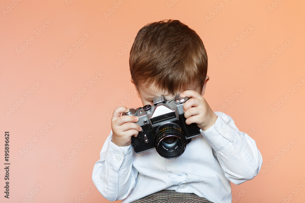 Naklejka premium Little boy with aged retro camera. Child with an old camera