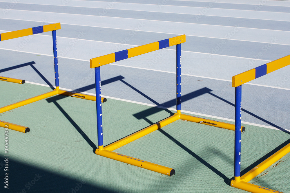 Naklejka premium Yellow blue jumping hurdles on running track