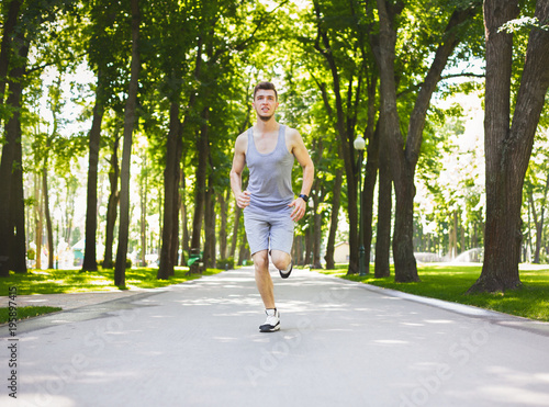 Young man running in green park, copy space