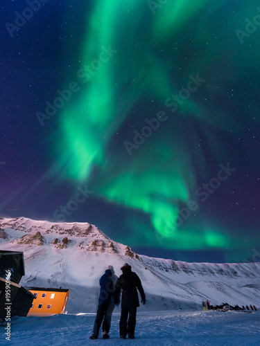 The polar arctic Northern lights aurora borealis sky star in Norway Svalbard in Longyearbyen city man people mountains photo