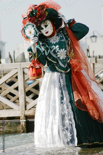 woman in beautiful red green and white masquerade dress and mask at the Venice carnival Italy