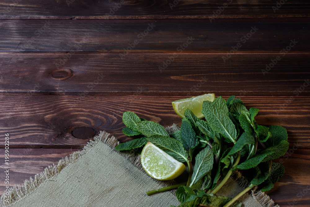 Bundle of fresh mint and lime slice on a napkin on an old wooden background. Bundle of fresh mint and lime slice on a napkin on an old wooden background.