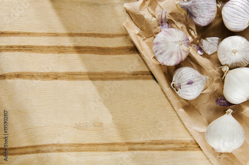 Small heads of garlic scattered on wooden background on kraft paper