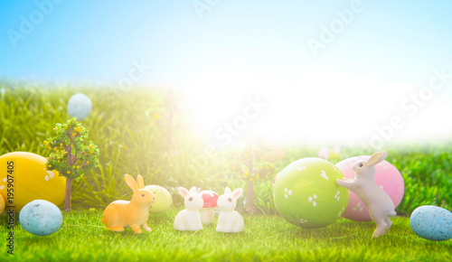 Little Easter bunny toys and Easter eggs on green grass photo