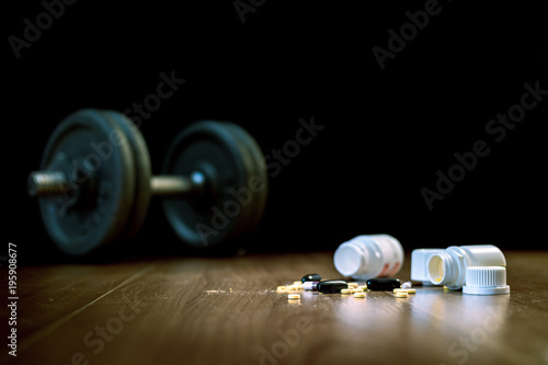 Foto Steroid pills and capsules with dumbbell weight in the background - doping in sport