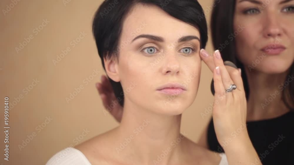 The make-up artist strikes the last strokes of a beautiful young model, close-up. The make-up artist strikes the last strokes of a beautiful young model, close-up.