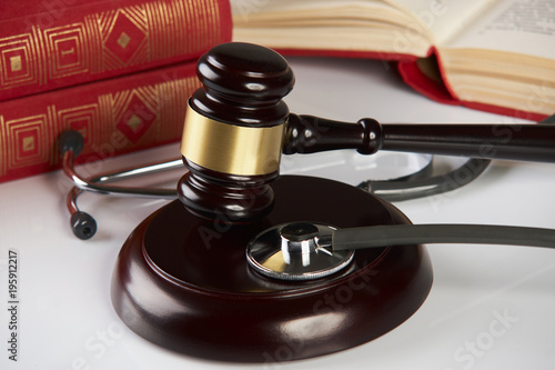 Judges gavel with law books and medical stethoscope on white table in a courtroom or enforcement office, close-up. selective focus. Medicine law concept