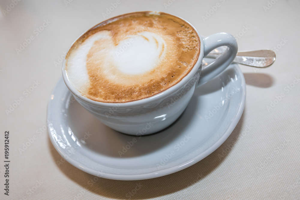 Cappuccino mit Milchschaum in Tasse auf Tischdecke Cappuccino mit Milchschaum in Tasse auf Tischdecke