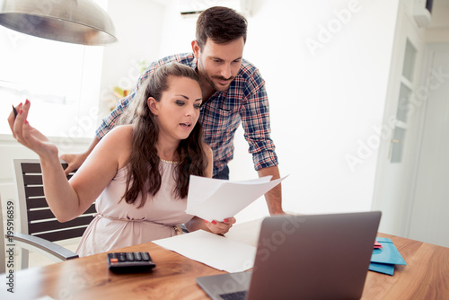 Couple at home paying bills with laptop