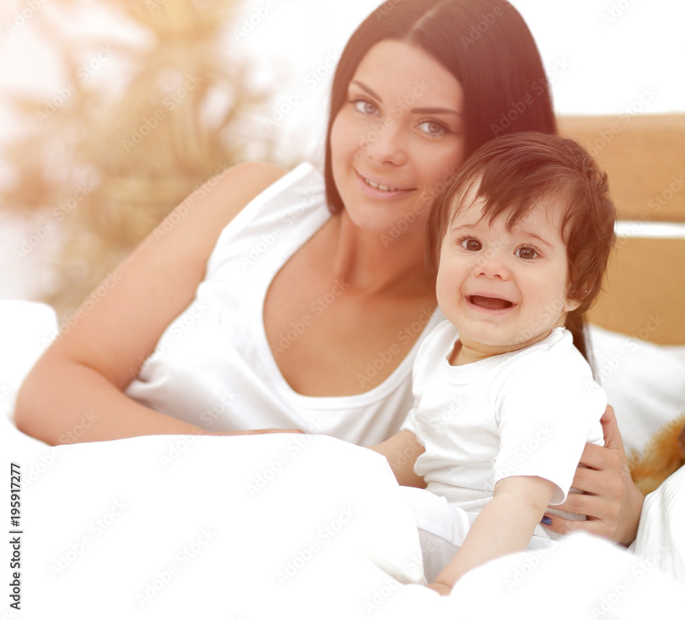 Portrait of a beautiful mother with her baby in the bedroom Portrait of a beautiful mother with her baby in the bedroom