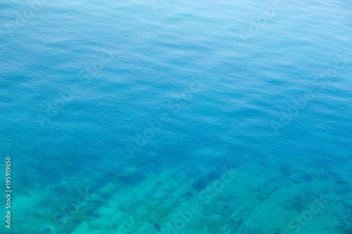 The texture of the water. Clear blue sea water with a stone slab on the bottom.