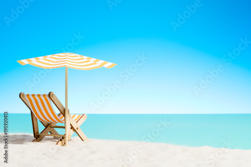 A chaise longue under an umbrella on the sandy beach by the sea and sky with copy space