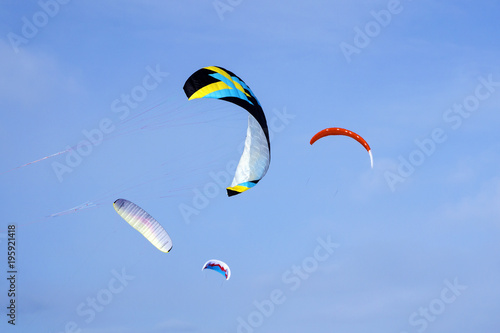 four bright multicolored sports kites for kiting or snowkiting against the blue sky..