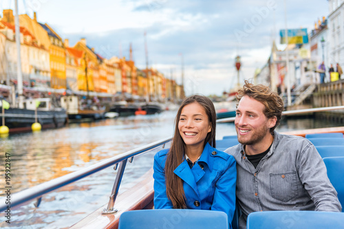 Copenhagen tourists people on Denmark travel holiday cruise boat tour in old port. Young multiracial couple travelers relaxing enjoying view of Nyhavn danish destination in Europe, fall or spring. © Maridav