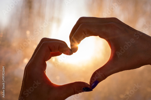 Female hands in the form of heart against the window pass sun beams. Hands in shape of love heart , silhouetted against the sun