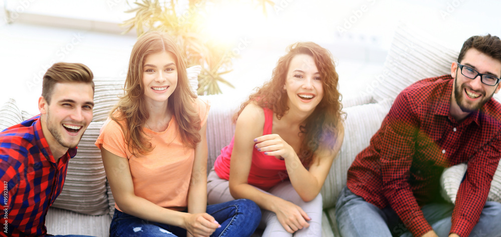 Obraz premium group of cheerful friends watching videos, sitting on the couch