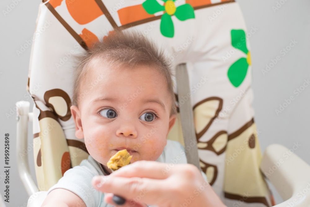 Blue-eyed baby boy eating in the baby's chair. Blue-eyed baby boy eating in the baby's chair.