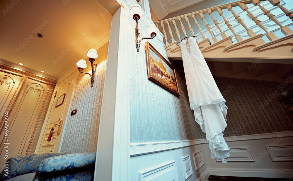 Elegant wedding dress hanging in the hotel room Elegant wedding dress hanging in the hotel room