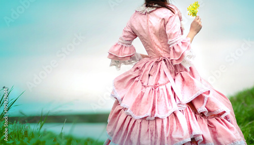 Fairy tale portrait of a beautiful princess woman in medieval era dress with yellow flowers in her hands photo