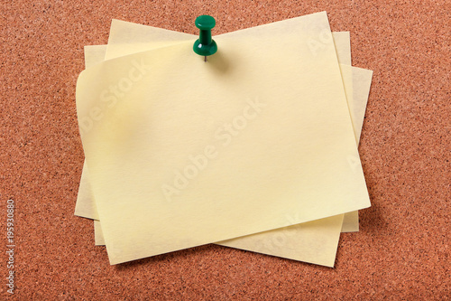 Pile stack or heap several yellow sticky post it note oblong on a cork notice or bulletin board background photo