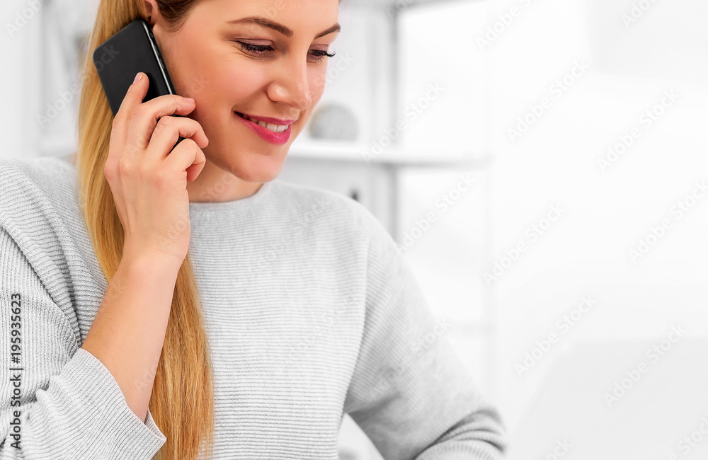 Attractive young woman with a smartphone in her hand at the office desk with a laptop. Attractive young woman with a smartphone in her hand at the office desk with a laptop.