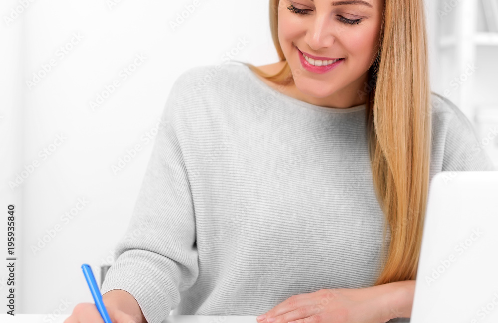 Beautiful woman is working with charts sitting at the table with a laptop. Work at home or in the office.