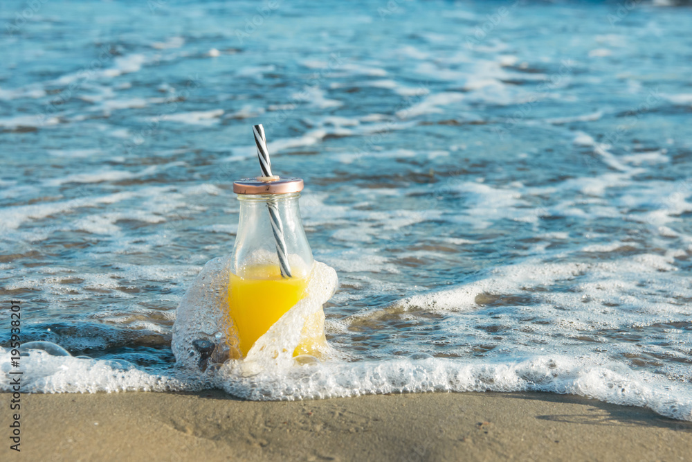 Glass Bottle with Freshly Pressed Tropical Fruits Juice with Straw Standing on Beach Sand Washed by Blue Turquoise Foamy Sea Waves. Golden Sunlight. Vacation Relaxation Freshness Summer Glass Bottle with Freshly Pressed Tropical Fruits Juice with Straw Standing on Beach Sand Washed by Blue Turquoise Foamy Sea Waves. Golden Sunlight. Vacation Relaxation Freshness Summer