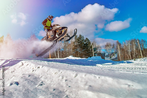 Sport yellow snowmobile jump. Cloud of snow dust from under snowmobile tracks. Concept quick movement. photo