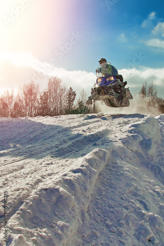 Sport blue snowmobile jump. Clear sunny winter day. Concept quick movement. Extreme sport background for any purposes. photo