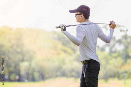 Asian couple playing golf. Man teaching woman to warm up while standing on field