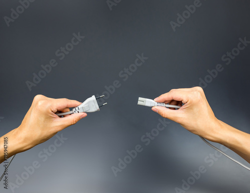Plug and socket on hands holding on grey grey background