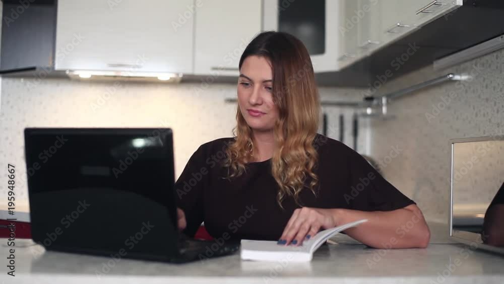 Beautiful young business woman working at a computer with a diary. HD Beautiful young business woman working at a computer with a diary. HD