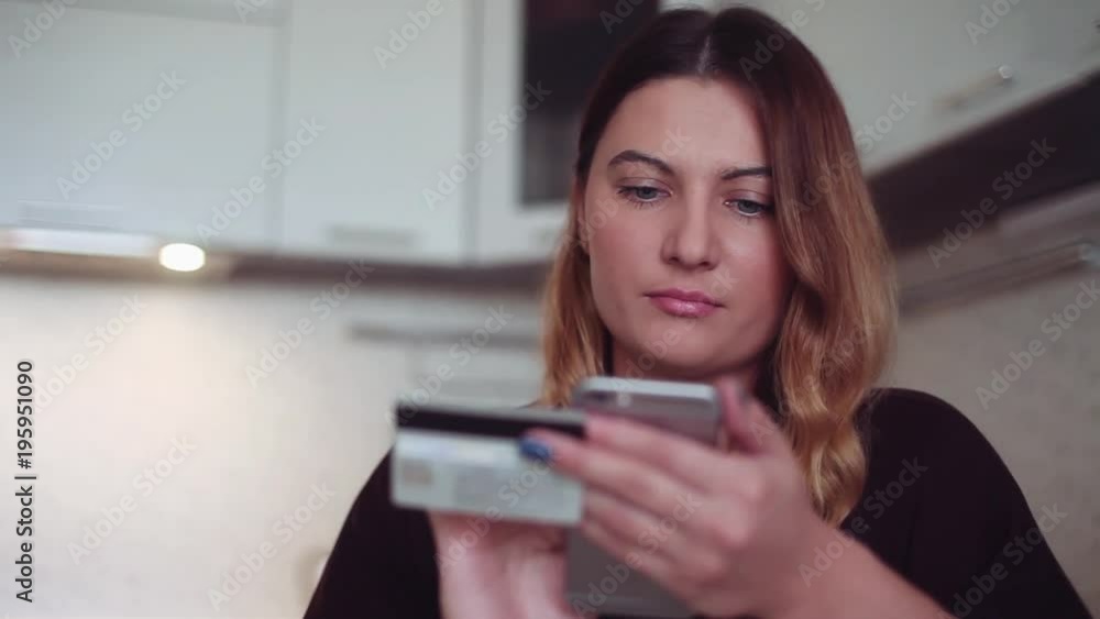 Beautiful woman online banking using smartphone shopping online with credit card at home lifestyle. The girl buys clothes on the Internet. Online shopping on the Internet through a mobile device. Beautiful woman online banking using smartphone shopping online with credit card at home lifestyle. The girl buys clothes on the Internet. Online shopping on the Internet through a mobile device.