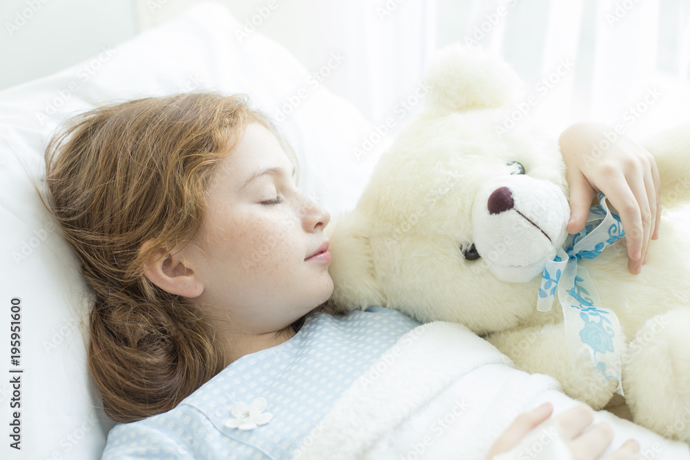 Girl sleeping and sick on the bed with teddy doll in her hand at hospital. Healthcare and medical concept.