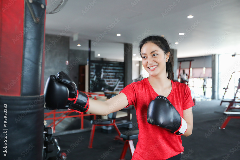 Beautiful women asian boxer happy and fun fitness boxing and Punching A Bag With wearing boxing gloves.