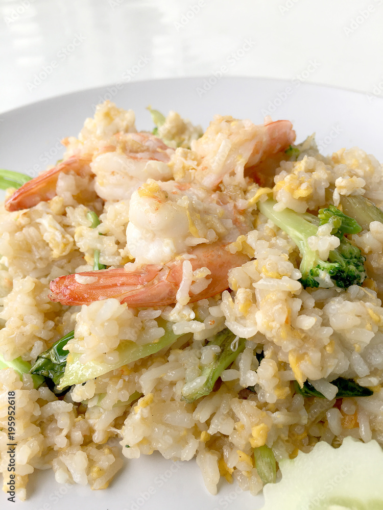 Fried rice with prawn herbs and vegetables served with lemon and cucumber in white plate on white background. Part of a series of nine Asian food dishes. Thai Food. Fried rice with prawn herbs and vegetables served with lemon and cucumber in white plate on white background. Part of a series of nine Asian food dishes. Thai Food.