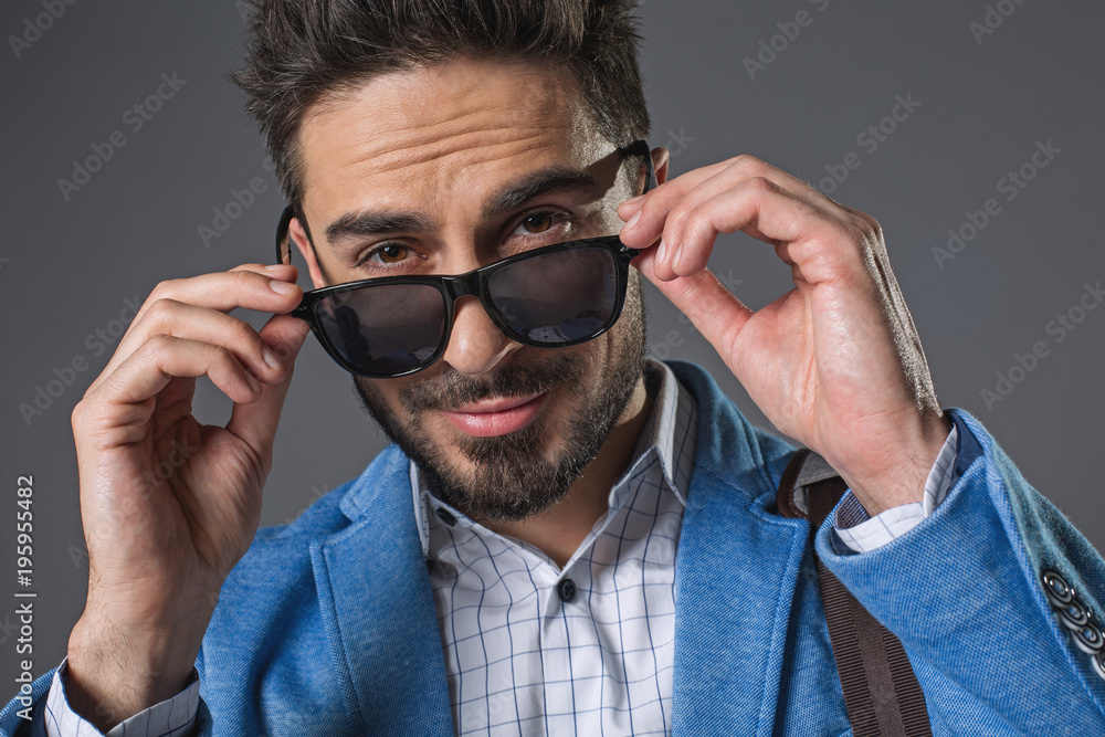 Φωτογραφία Waist up portrait of self-confident successful businessman touching-up shades glasses