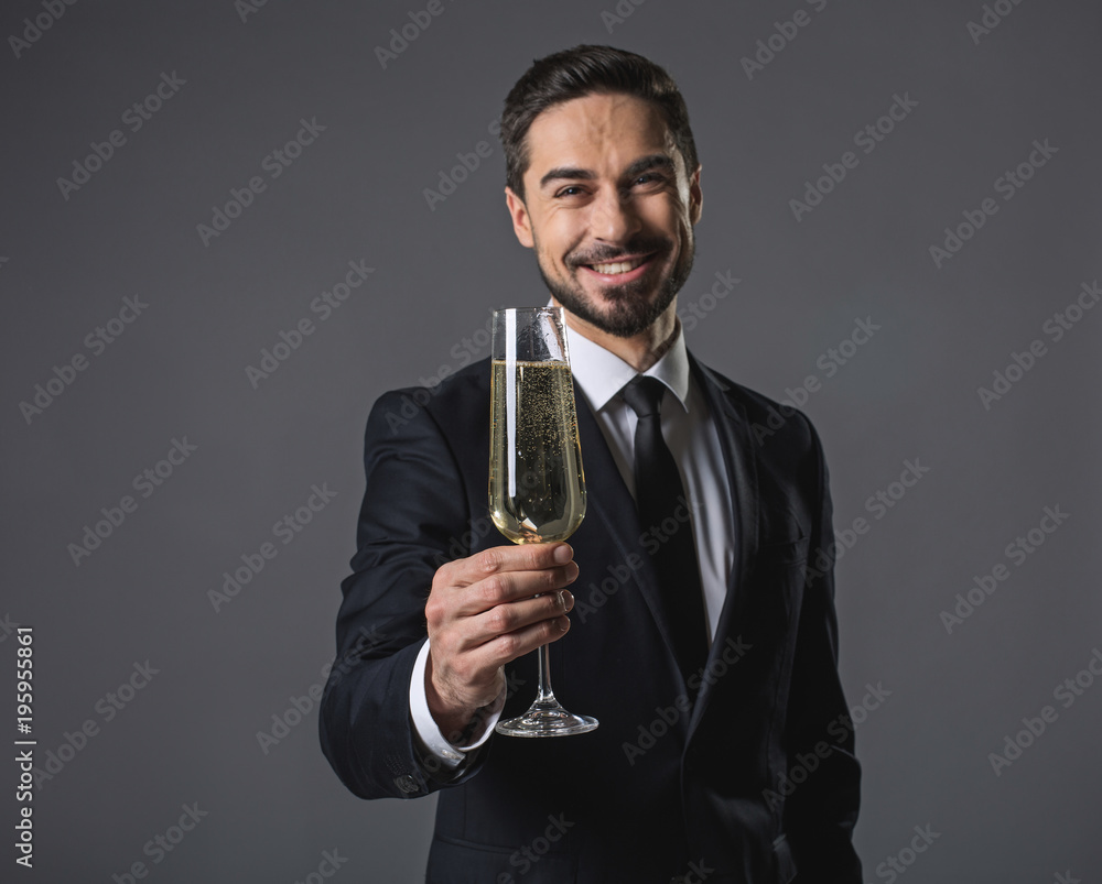 Φωτογραφία Waist up portrait of young cheerful man in suit standing and holding in hand wineglass