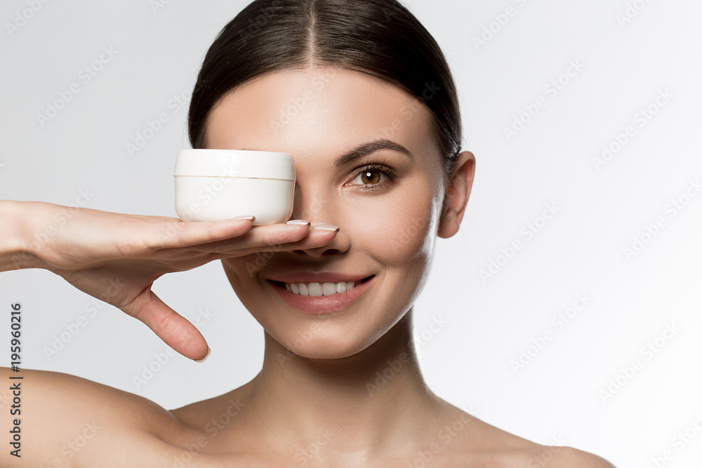 Portrait of joyful girl covering her eye by a cream can. She is looking at camera and laughing. Isolated Portrait of joyful girl covering her eye by a cream can. She is looking at camera and laughing. Isolated