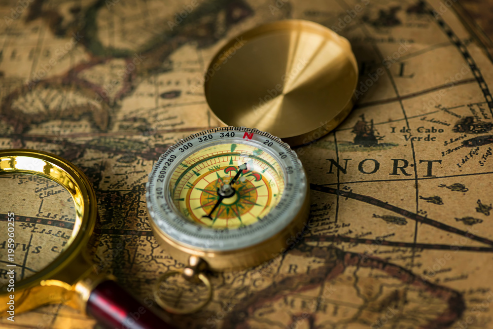 Retro compass with old map and magnifier