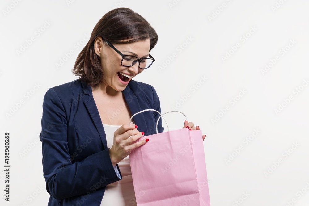 Surprised adult woman looking shopping bag, white background Surprised adult woman looking shopping bag, white background
