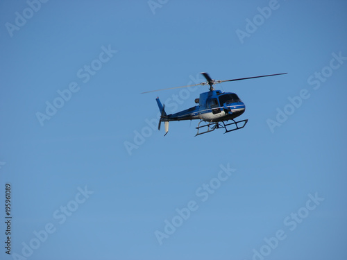 Blue helicopter flying on blue sky