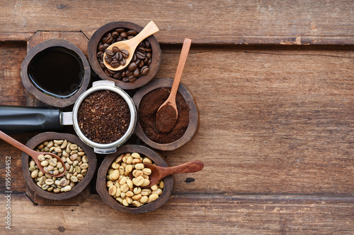 Freshly ground coffee beans in a metal filter and coffee beans in bowl on wooden background